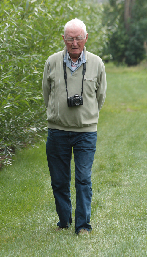 Bas wandelt in de boomgaard van zijn zwager in Piershil met zijn fototoestel om zijn nek.